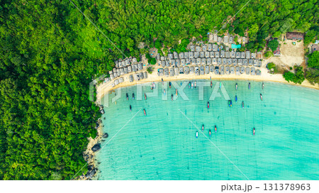 A stunning aerial view of a tropical beach village with rows of small huts along the coastline, 131378963