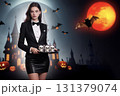 A beautiful woman in a black tuxedo invites guests to a Halloween party. 131379074