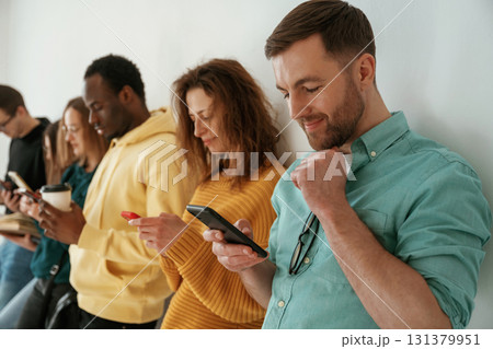 Busy by using smartphones. Group of young people are standing against white background 131379951