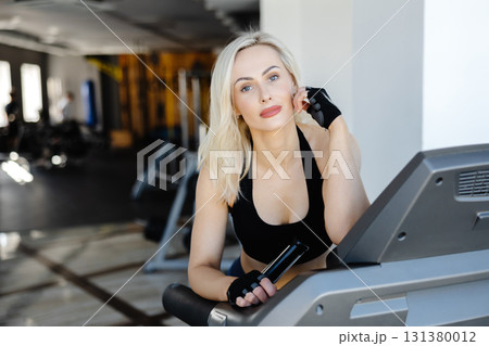 Determined sportswoman running on treadmill during fitness workout in gym Determined sportswoman running on treadmill during fitness workout in gym 131380012