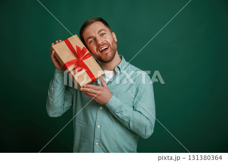 Little gift box in hands. Man is standing against background in the studio 131380364