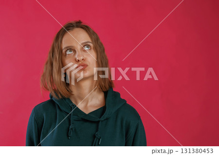 Making funny faces. Young woman is standing against red background in the studio Making funny faces. Young woman is standing against red background in the studio 131380453