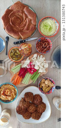 Colorful vegetarian potluck dinner with hummus, falafel, pie, and fresh vegetables, flatlay mobile photo. Concept of food, cuisine, meal, authenticity. 131380743