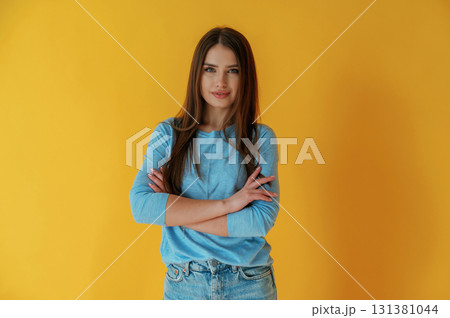 Confident look, portrait. Young woman is against yellow background Confident look, portrait. Young woman is against yellow background 131381044