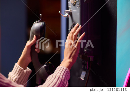 A Person Using a Payphone at Night in an Urban Setting, Highlighting Nostalgic Communication 131381118