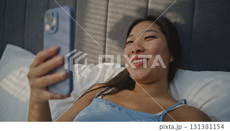 Smiling Woman Chatting on Video Call From Bedroom Smiling Woman Chatting on Video Call From Bedroom 131381154