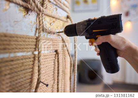 A skilled handyman is using a powered drill on a textured wall to enhance home improvement A skilled handyman is using a powered drill on a textured wall to enhance home improvement 131381162