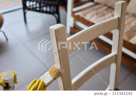 Engage in DIY chair restoration using a paint brush and protective gloves for the process 131381242