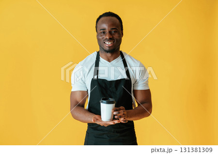 Cafe worker. Black man is in the studio against yellow background 131381309