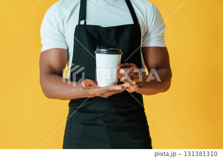 Cafe worker. Black man is in the studio against yellow background 131381310
