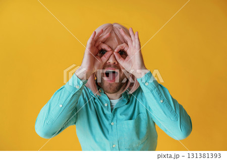 Making facial expression, hand gestures. Guy with pink hair is posing against yellow background 131381393