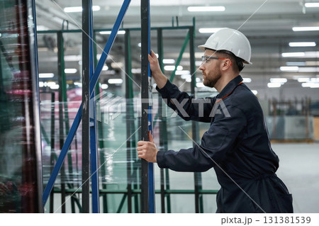 Moving the parts of windows. Factory worker is indoors with hard hat 131381539