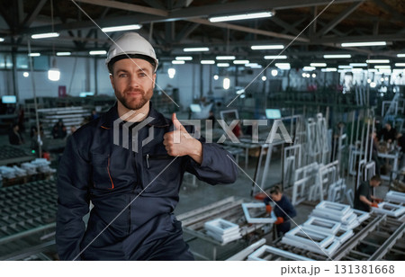Gesture of thumb up. Factory worker is indoors with hard hat 131381668