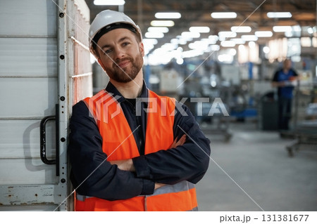 Leaning on the wall. Factory worker is indoors with hard hat Leaning on the wall. Factory worker is indoors with hard hat 131381677