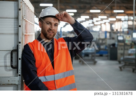 Leaning on the wall. Factory worker is indoors with hard hat 131381678