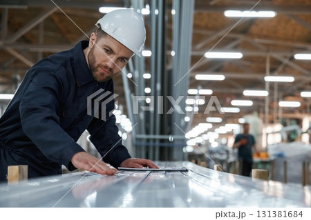 Checking quality of material, control. Factory worker is indoors with hard hat Checking quality of material, control. Factory worker is indoors with hard hat 131381684