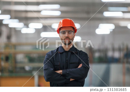 Focused portrait, in glasses. Factory worker is indoors with hard hat 131381685