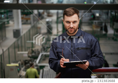 Writing information into the notepad. Factory worker is indoors with hard hat Writing information into the notepad. Factory worker is indoors with hard hat 131381688