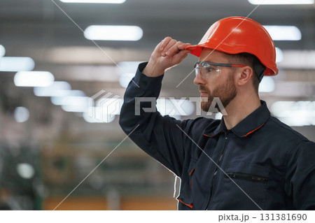 Blurred background. Factory worker is indoors with hard hat Blurred background. Factory worker is indoors with hard hat 131381690