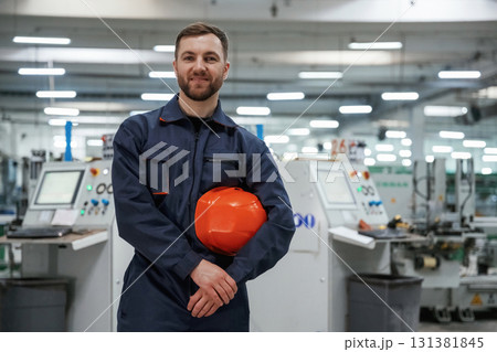 Break time, standing. Factory worker is indoors with hard hat Break time, standing. Factory worker is indoors with hard hat 131381845