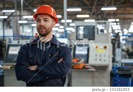 Confident facial expression. Factory worker is indoors with hard hat Confident facial expression. Factory worker is indoors with hard hat 131381855