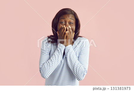 Portrait of young african american woman embarrassed and hiding her laughter and face with hands. 131381973