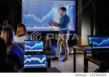 Graph is going up. Male business trainer is against projector with data, teaching people Graph is going up. Male business trainer is against projector with data, teaching people 131383025