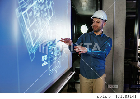Modern exterior. Man architect in hard hat is near projector with construction plan Modern exterior. Man architect in hard hat is near projector with construction plan 131383141
