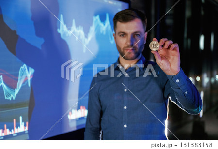 Digital currency, holding coin in hand. Business coach against projector with data 131383158
