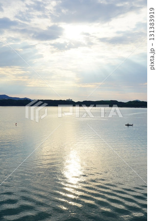 光り輝く朝日が湖面を照らし小さなボートが浮かぶ幻想的な浜名湖の縦構図写真 光り輝く朝日が湖面を照らし小さなボートが浮かぶ幻想的な浜名湖の縦構図写真 131383919