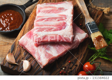 Raw pork ribs with spices, salt and rosemary on dark wooden background Raw pork ribs with spices, salt and rosemary on dark wooden background 131384022