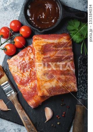 Ready for BBQ raw pork spare ribs with barbecue sauce. Black background. Top view Ready for BBQ raw pork spare ribs with barbecue sauce. Black background. Top view 131384034