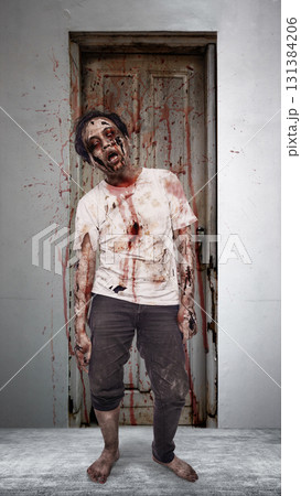 Scary male zombie with a wound and bloody standing in front of the old wooden door with splatters of blood drops on it. The scene is scary and creepy. Concept of Spooky Halloween Scary male zombie with a wound and bloody standing in front of the old wooden door with splatters of blood drops on it. The scene is scary and creepy. Concept of Spooky Halloween 131384206