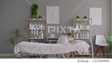 Minimalist massage clinic interior with treatment table, cosmetics and greenery Minimalist massage clinic interior with treatment table, cosmetics and greenery 131384404