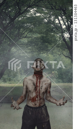 Scary male zombie with a wound and blood walking on the street surrounded by trees. The scene is scary and creepy. Dramatic smoke or fog effect. Concept of Spooky Halloween Scary male zombie with a wound and blood walking on the street surrounded by trees. The scene is scary and creepy. Dramatic smoke or fog effect. Concept of Spooky Halloween 131384463
