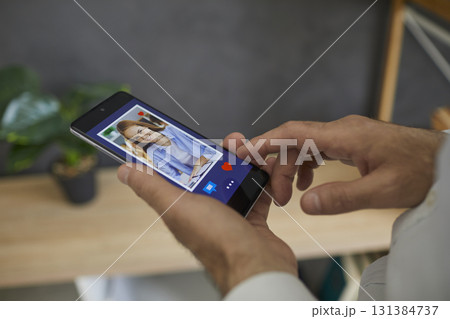 Man looks through a photo of a young European woman on his smartphone, clicks I like it Man looks through a photo of a young European woman on his smartphone, clicks I like it 131384737