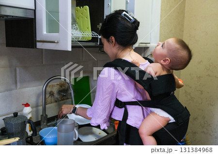 Mother Washing Dishes with Baby on Her Back 131384968