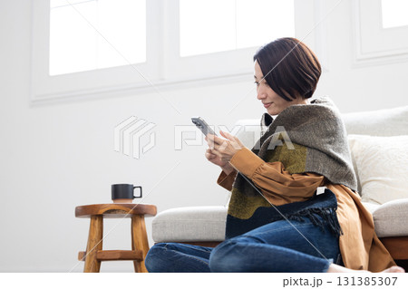 リビングでスマートフォンを操作するミドル女性 131385307