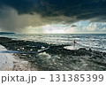 怪しい天気の中、サーフボードを持って海に入るサーファー 131385399