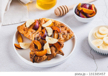 Croissant waffles with fruit and honey on a plate on a table 131385457
