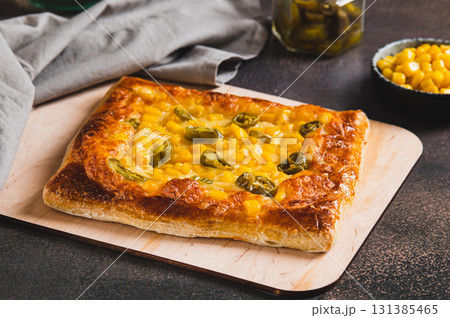 Spicy pizza with jalapeno pepper, corn and cheese on a wooden board Spicy pizza with jalapeno pepper, corn and cheese on a wooden board 131385465
