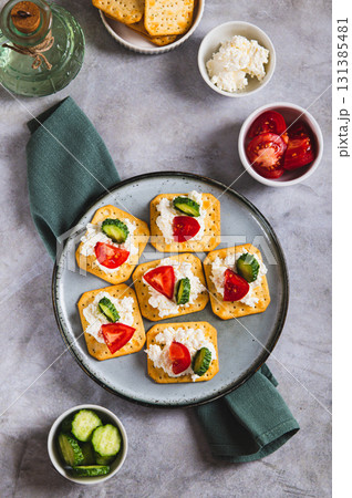 Cottage cheese and vegetables on crackers on a plate on the table top and vertical view Cottage cheese and vegetables on crackers on a plate on the table top and vertical view 131385481