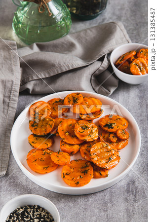 Fried carrots in spices and garlic on a plate on the table vertical view Fried carrots in spices and garlic on a plate on the table vertical view 131385487