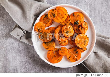 Close up of pieces of fried carrots with garlic and herbs on a plate on the table top view 131385489