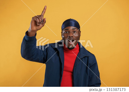 Pointing by the finger to copy space. Handsome black man is in the studio against yellow background Pointing by the finger to copy space. Handsome black man is in the studio against yellow background 131387173