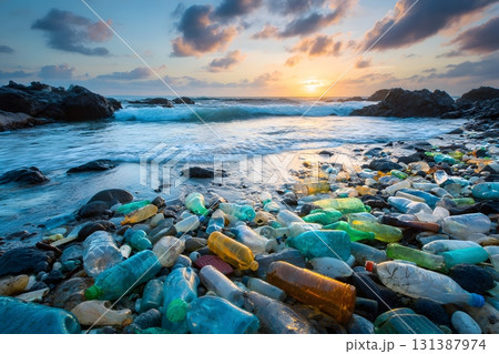 Ocean waves wash over plastic bottles littering a rocky beach at sunset. Ocean waves wash over plastic bottles littering a rocky beach at sunset. 131387974