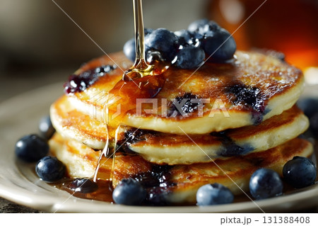 Stack of blueberry pancakes with syrup pouring over them. 131388408