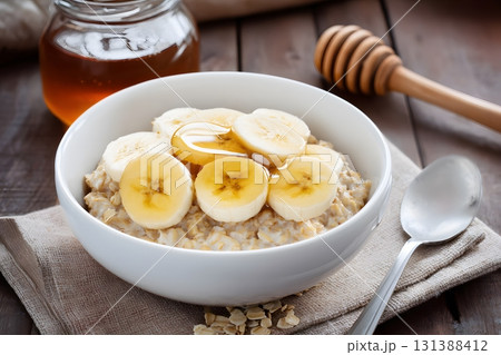 Bowl of oatmeal with banana slices and honey is ready to eat. 131388412