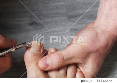He cuts his toenails with scissors and wire cutters. Manicure at home He cuts his toenails with scissors and wire cutters. Manicure at home 131388721