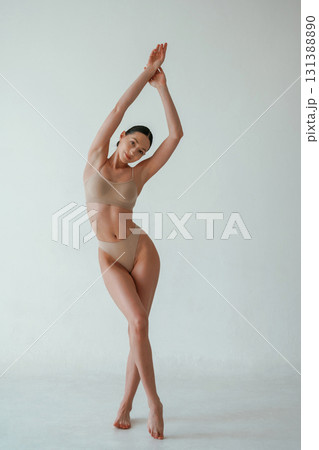 With hands up. Woman with slim body shape is posing against background With hands up. Woman with slim body shape is posing against background 131388890